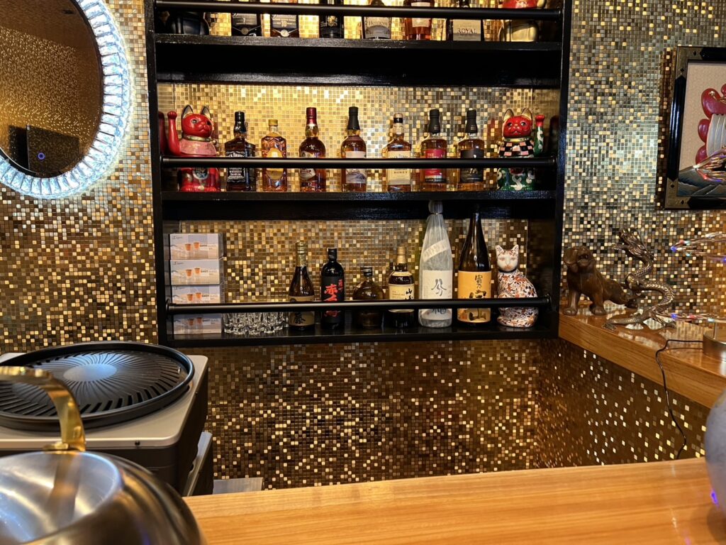 金のモザイクタイルと黒の造作酒棚を組み合わせたバーカウンター