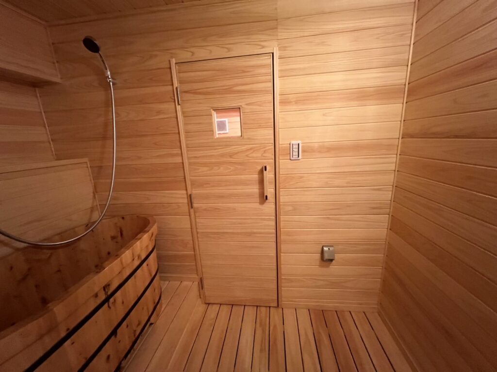木製の浴槽とシャワーを備えた、羽目板張りの浴室
