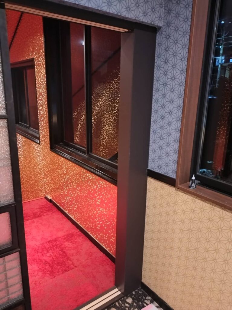 麻の葉柄のクロスの廊下から見た、赤と金の壁のお部屋