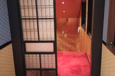 麻の葉柄のクロスの壁に納めた格子の引き戸と、その先の赤いお部屋