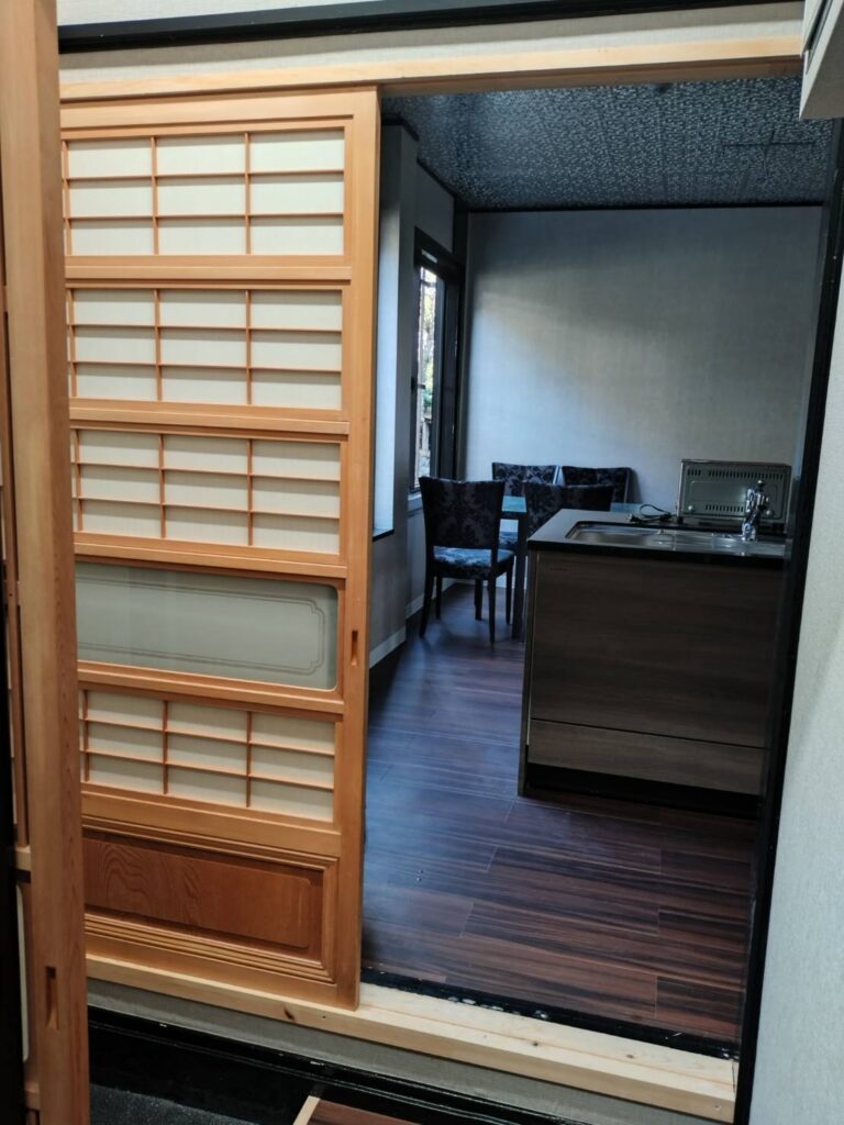 木の引き戸を開けた先の、木目調のフロアのダイニングキッチン